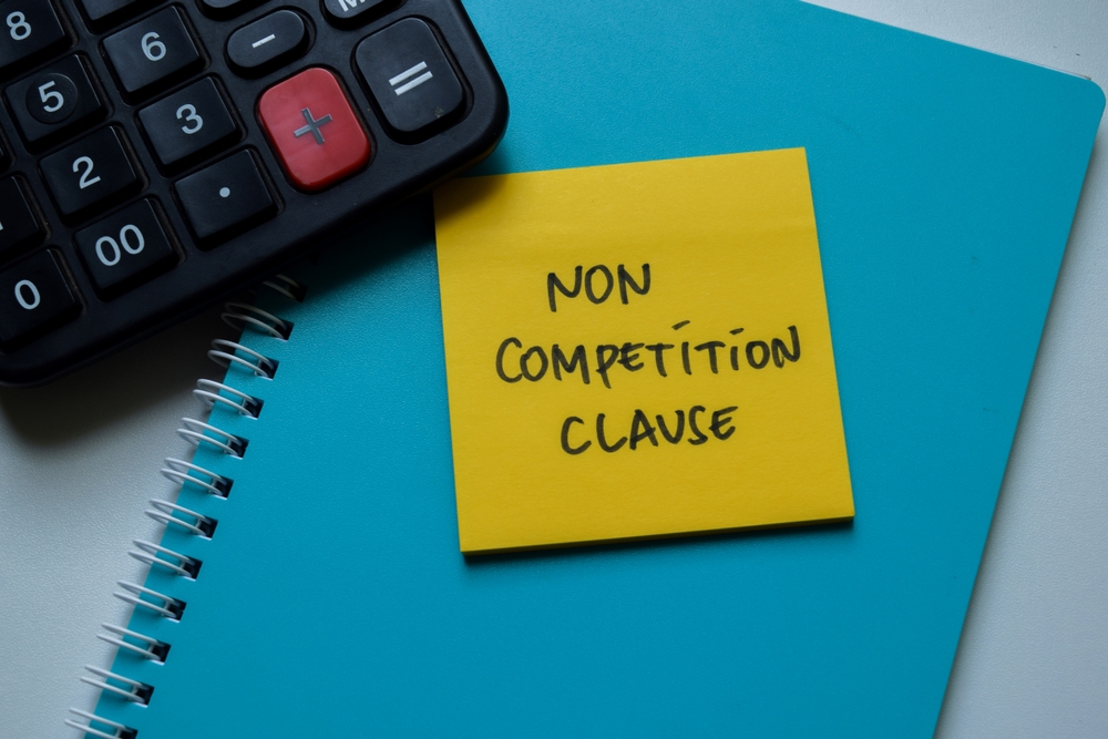 Non Competition Clause write on sticky notes isolated on Wooden Table
