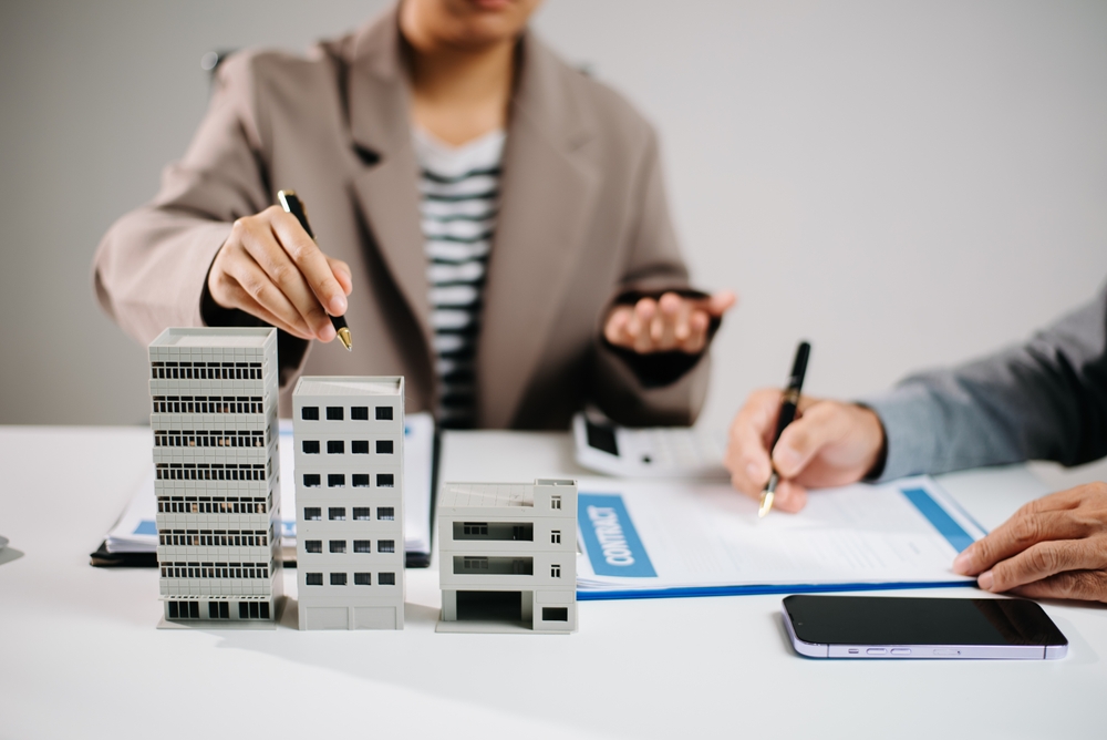 Real estate agent and investor discussing commercial property contract with building model
